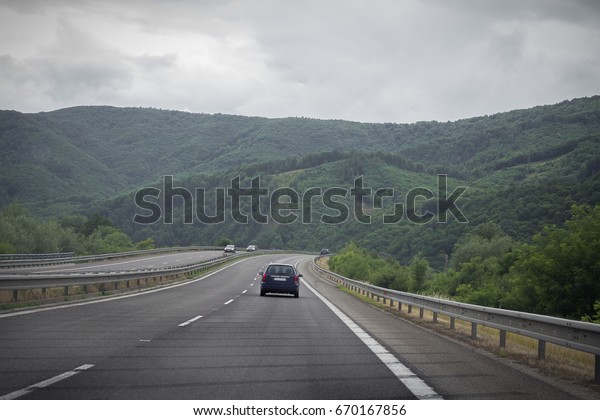 Asphalt\
road and car in the mountains with cloudy\
sky
