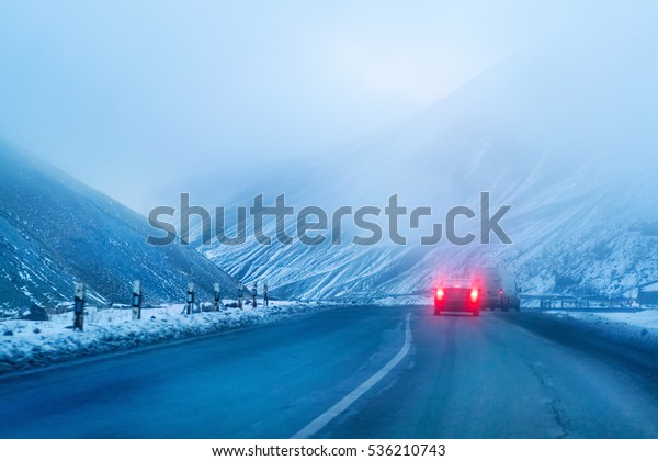 Asphalt road with\
cars in the mountains at\
dusk