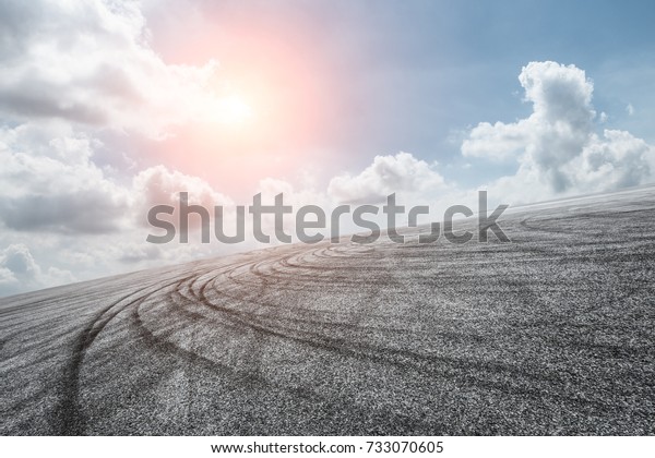 Asphalt\
road circuit and sky clouds with car tire\
brake
