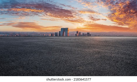 Asphalt road and city skyline with modern commercial building at sunset in Suzhou, China. 