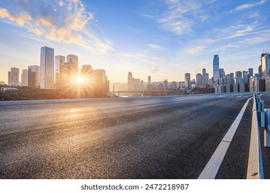 Asphalt road and city skyline with modern buildings in Chongqing at sunrise.