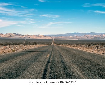 Asphalt Road With Diminishing Perspective Heading Down Through Death Valley California In Late Autumn.