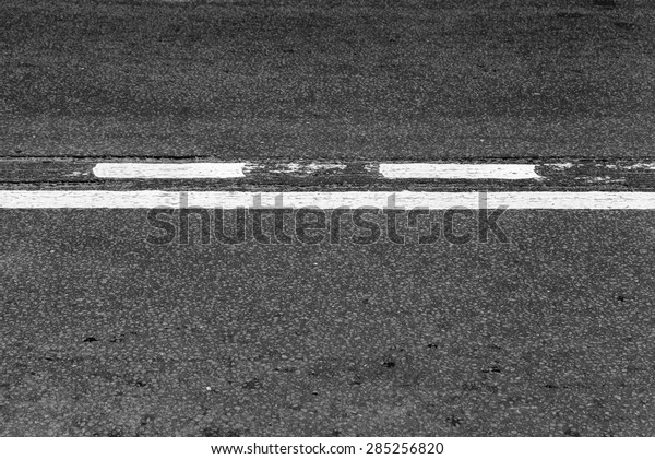 Asphalt road with\
dividing line and tire tracks. Abstract transportation background\
with selective focus