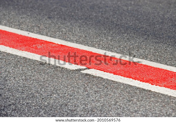Asphalt road. Double lane road stripes white and\
red. Selective focus