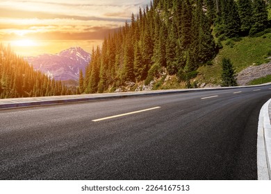 Asphalt road and green forest with mountain natural scenery at sunset in Xinjiang, China. - Powered by Shutterstock