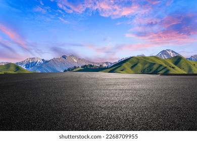 Asphalt road and green mountain natural scenery at sunset in Xinjiang, China.