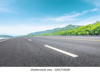 Asphalt Road And Green Mountain Under The Blue Sky