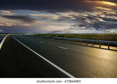 Asphalt Road High Way Empty Curved Road Clouds And Sky At Sunset
