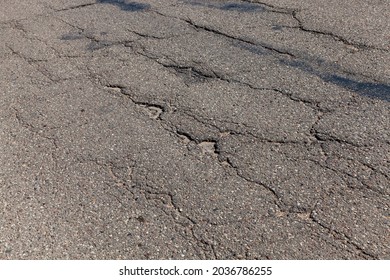 An Asphalt Road With A Lot Of Holes And Damage, A Poorly Made Collapsing Asphalt Road