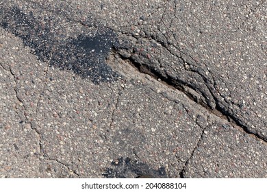 An Asphalt Road With A Lot Of Holes And Damage, A Poorly Made Collapsing Asphalt Road