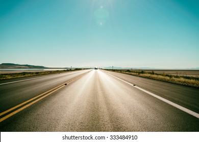 Asphalt road to the horizon line under a burning Sun