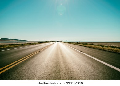 Asphalt Road To The Horizon Line Under A Burning Sun