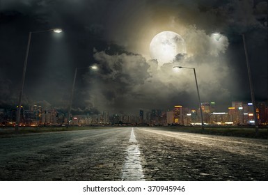 asphalt road leading into the city at night - Powered by Shutterstock