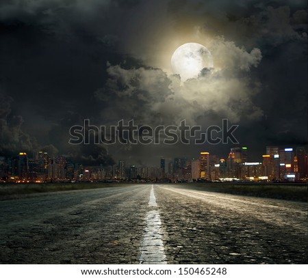 asphalt road leading into the city at night