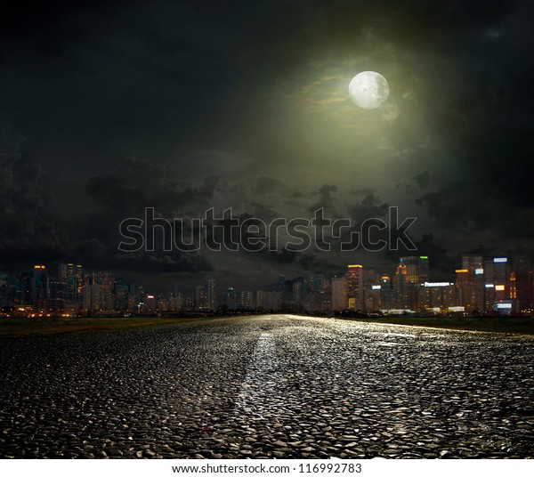 asphalt road leading\
into the city at night
