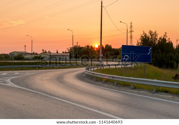 Asphalt\
road makes a right turn against the setting\
sun