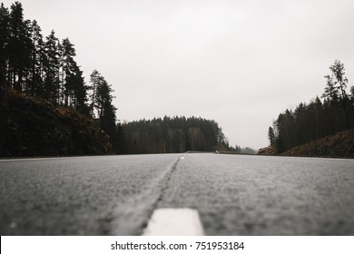 Asphalt road in the middle with a light fog in the rainy weather low shot. A low angle shot at the middle of an empty road.