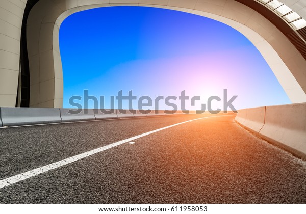 Asphalt road and\
modern architecture at\
sunset