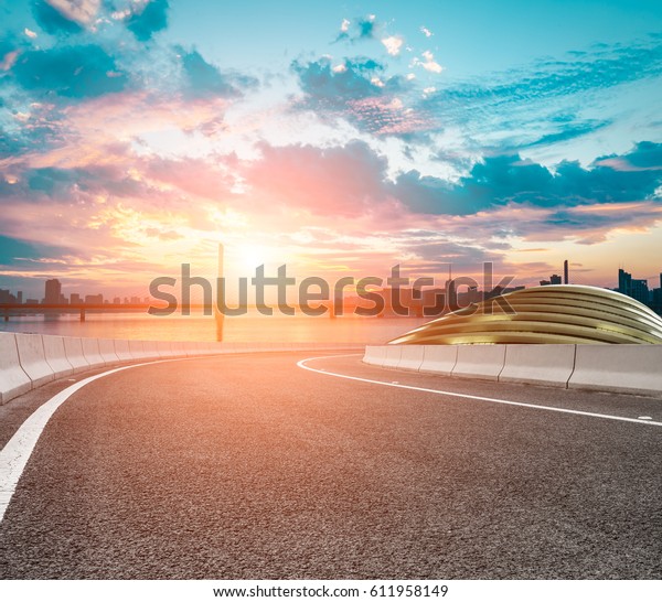 Asphalt road and\
modern architecture at\
sunset