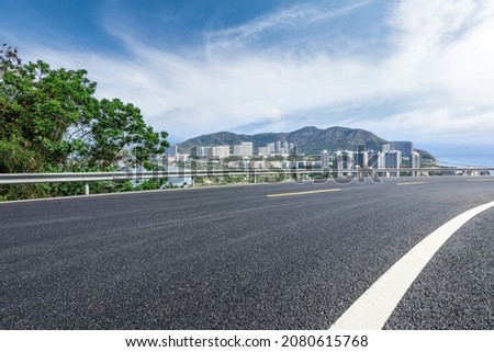 Asphalt road and modern city commercial buildings with skyline by the sea