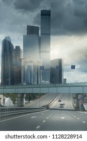 Asphalt Road To The Modern City. Dark Stormy Clouds And A Sum Beam