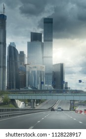 Asphalt Road To The Modern City. Dark Stormy Clouds And A Sum Beam