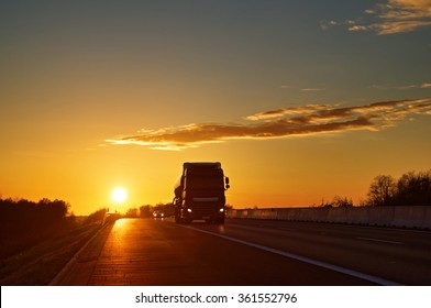 Asphalt Road With Oncoming Truck In A Rural Landscape At Sunset.