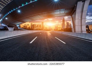 Asphalt road and pedestrian bridge with modern city skyline at sunset in Ningbo, Zhejiang Province, China.