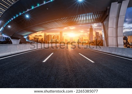 Asphalt road and pedestrian bridge with modern city skyline at sunset in Ningbo, Zhejiang Province, China.