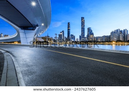Asphalt road and pedestrian bridge with modern city buildings at night in Guangzhou