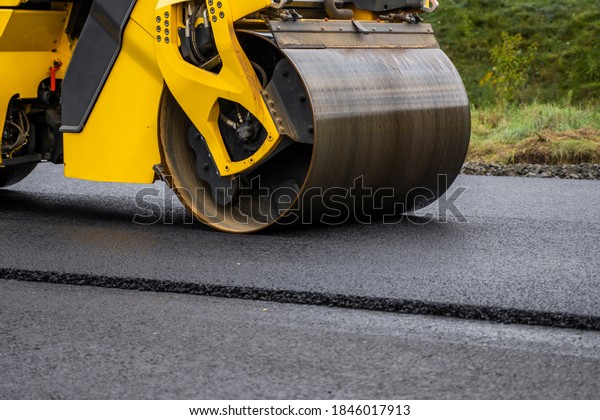 Asphalt\
road roller with heavy vibration roller compactor press new hot\
asphalt on the roadway on a road construction site. Heavy Vibration\
roller at asphalt pavement working.\
Repairing.