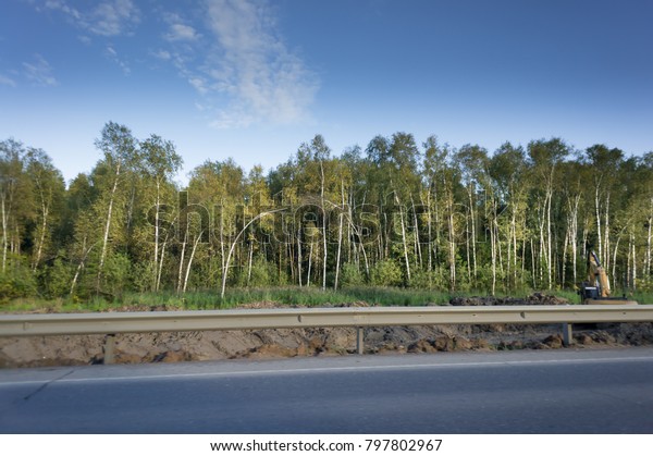 asphalt road with\
safety barrier and\
forest.