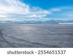 Asphalt road square and city skyline with mountain nature scenery under blue sky. Outdoor asphalt parking lot.