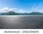 Asphalt road square and lake water with green mountain nature landscape under blue sky. Outdoor asphalt parking lot.