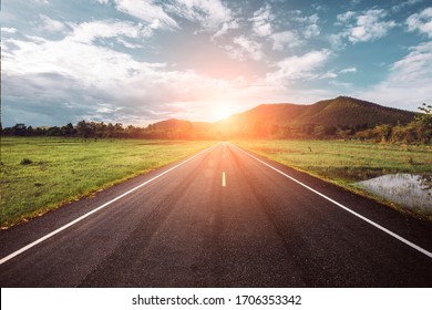 Asphalt road through the green field and clouds on blue sky in summer day. Beautiful grassland road in Thailand.Highland road.