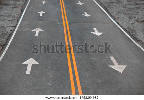Asphalt Road with Two Yellow\
Dividing Lanes and Arrows Drawn on the Asphalt Indicating The\
Direction of Movement. Concept of Traffic Rules, Motivation,\
Business
