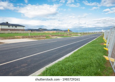Asphalt road with vacant lands on side in a new residential suburb. Tarneit, Melbourne, VIC Australia. Concept of real estate development, housing, urbanization and land for sale.