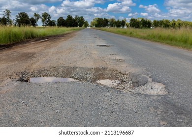 Asphalt Road With A Very Large And Deep Pothole. Pothole Is Half Filled With Water. 