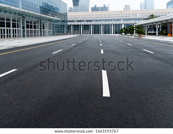 Asphalt road with white\
dashed lines.