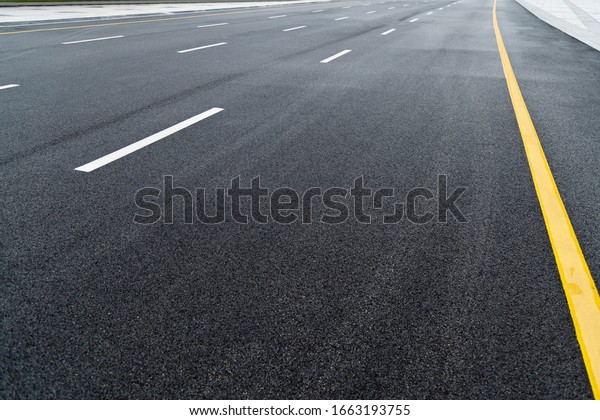 Asphalt road\
with white stripes and yellow\
lines.