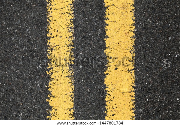 Asphalt road with yellow double\
dividing line, top view. Transportation background\
texture