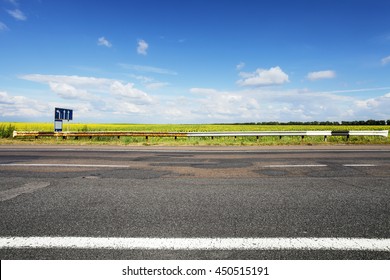 Asphalt Rough Road. Field Of Sun Flowers On Horizon. Summer Landscape