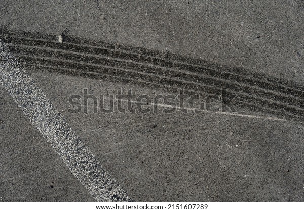 Asphalt texture\
with white line and tire marks. Smooth asphalt road. Tarmac dark\
grey grainy road background.Top\
view