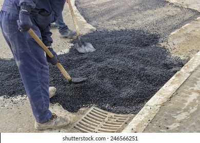 Asphalt Workers With Shovels Patching Asphalt During Road Repairing Works. Selective Focus.