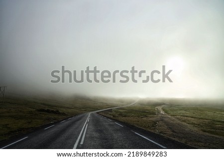 An asphalted countryside road under the misty sky