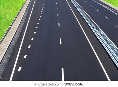 Asphalted Highway. Empty Motorway. High-speed Road Of The City. Barrier, Guarding Rail. Perspective, Convergence, Top View. Rainwater Drainage System, Runoff, Green Grass On The Roadside