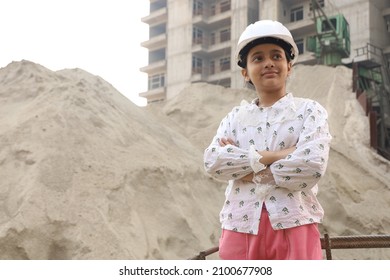 Aspirational Indian Female Child Engineer Standing On A Construction Site. Confident Girl Standing Wearing A Construction Helmet.