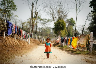 ASSAM, INDIA FEBRUARY 4 2016: an unidentified young girl is possing to camera in a long unmade road at assam's tea plantations