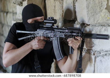 Assault automatic rifle in the hands of an abstract enemy in black clothes and in the mask
