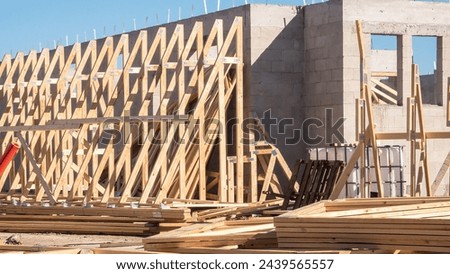Assemblage of prebricated wooden roof trusses for placement on concrete shell of a single-family house under construction in a suburban development on a sunny morning in southwest Florida